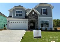 Charming two-story home featuring a stone-accented entryway, light-gray siding, and a two-car garage on a well-manicured lawn at 2204 Camber Dr # Cwo0076, Gastonia, NC 28054