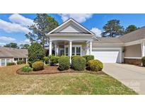 Charming home showcasing a manicured front yard with mature landscaping and inviting covered entry at 3008 Sweetleaf Dr, Fort Mill, SC 29707