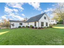 Charming white house with a well-manicured lawn, accented by colorful shrubs and a bright blue sky at 317 Commodore Loop, Mooresville, NC 28117