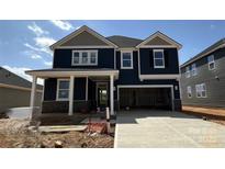 Beautiful two-story navy blue home featuring a covered front porch and two-car garage with gray accents at 334 Knotty Wood Dr # 68, Monroe, NC 28110