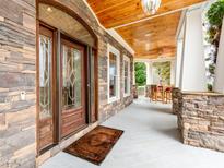 Inviting front porch with stone accents, wood ceiling, and seating area at 123 Yellow Jacket Cir, Mooresville, NC 28117