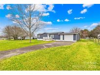 Charming home featuring a well-maintained lawn, attached garage, and inviting front porch at 133 Hallmark Estates Dr, Statesville, NC 28625