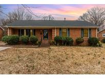 Charming single-story brick home featuring manicured bushes and neutral-colored trim at 4815 Carriage Drive Cir, Charlotte, NC 28205