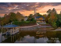 Stunning lakefront home with boat dock and lush landscaping at sunset at 6233 Riviera Run Estates Dr, Hickory, NC 28601