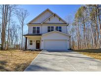 Two-story home with white siding, a two-car garage and a concrete driveway set against a backdrop of trees at 268 Lytton Farm Rd, Troutman, NC 28166