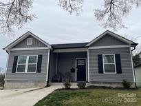 Charming home with gray siding, black shutters, covered entry, and manicured landscaping at 611 N York St, Gastonia, NC 28052