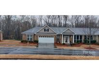Charming brick home with a well-manicured lawn and attached two-car garage, perfect for suburban living at 6914 Cinnamon Cir, Mint Hill, NC 28227