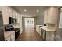Open-concept kitchen with white cabinets, stainless steel appliances, and seamless flow into the living area at 8703 Ellington Park Dr, Charlotte, NC 28277
