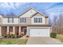 Charming townhome with a two-car garage, landscaped yard, and a welcoming front porch on a sunny day at 137 Woodbridge Cir, Mount Holly, NC 28120