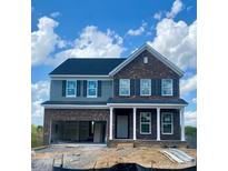 Two-story home featuring a brick facade, gray siding, a two-car garage, and a covered front porch, all under a blue sky at 13705 Roderick Dr # 194, Huntersville, NC 28078