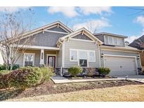 A view of the front of this lovely home featuring stone accents, neutral siding and mature shrubbery at 14827 Batteliere Dr, Charlotte, NC 28278