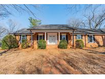 Charming brick home with inviting front porch and well-manicured landscaping at 4210 Wrangler Sw Dr, Concord, NC 28027