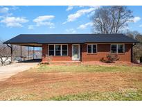 Charming single-story brick home with a dark metal roof and cozy front yard at 4386 Section House Rd, Hickory, NC 28601