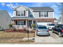 Charming two-story home with brick and siding, a welcoming front porch, and a well-maintained yard and driveway at 4716 Meadowfield Rd, Charlotte, NC 28215