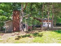Secluded home with a red brick chimney and attached two-car garage, surrounded by mature trees at 11101 Winding Way Rd, Charlotte, NC 28226