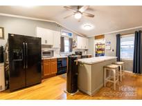Bright kitchen with hardwood floors, stainless steel refrigerator, and a breakfast bar area with seating at 115 Setter Ct, Statesville, NC 28625