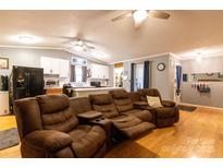 Spacious living room featuring hardwood floors, a modern kitchen, and a comfortable recliner couch at 115 Setter Ct, Statesville, NC 28625