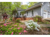 Charming home exterior with gray siding, brick foundation, and colorful flowering shrubbery at 140 Rustic Way Ln, Mooresville, NC 28117