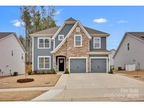 Charming two-story home featuring a mix of stone and gray siding, plus an attached two-car garage at 155 Autumnwood Rd, Troutman, NC 28166