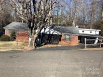 Charming brick ranch-style home with a screened porch and attached carport, surrounded by mature trees and landscaping at 314 Little St, Lincolnton, NC 28092