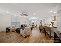 Open-concept living space features wood floors, a large sectional sofa, and modern decor at 3899 Center Place Dr, Harrisburg, NC 28075