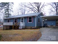 Charming one-story home with a covered front porch, mature trees, and a convenient carport at 522 Perry St, Troy, NC 27371