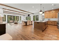 Open concept living space with wood beams, modern decor, and hardwood flooring at 5520 Chedworth Dr, Charlotte, NC 28210
