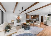 Open concept living room with wood beams, hardwood floors, modern furniture, and kitchen view at 5610 Farmbrook Dr, Charlotte, NC 28210