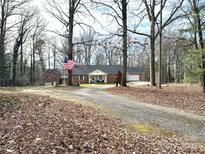 Traditional brick home with an American flag, gravel driveway, and mature trees at 583 Old Wilkesboro Rd, Taylorsville, NC 28681