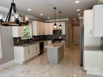 Bright kitchen with white cabinets, an island, stainless appliances, and elegant marble floors at 7221 Static Way # 13, Sherrills Ford, NC 28673