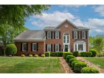 Traditional brick home with manicured lawn, black shutters, and lush landscaping creating a welcoming curb appeal at 1006 Baldwin Ln, Waxhaw, NC 28173