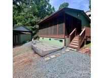 Backyard view showcasing a cozy screened-in porch, rock landscaping, and a storage shed at 152 Muskhogean Way, Mount Gilead, NC 27306