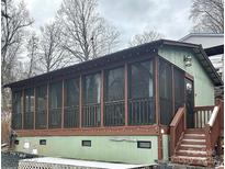 A screened porch with a brown wood frame is attached to a home with green siding and a gray sky above at 152 Muskhogean Way, Mount Gilead, NC 27306