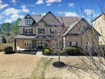 A beautiful two-story home featuring stone and brickwork, a covered porch, and manicured landscaping at 15637 Guthrie Dr, Huntersville, NC 28078
