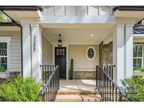 Inviting front porch with stone accents, black railing, and an oval window feature at 3288 Sherman Dr, Lancaster, SC 29720