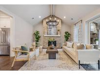 Inviting living room featuring a brick fireplace, vaulted ceiling, modern chandelier, and neutral decor at 3288 Sherman Dr, Lancaster, SC 29720