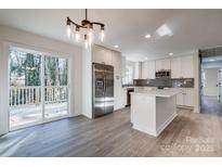 Modern white kitchen with stainless steel appliances and an island leading to an outdoor deck at 1522 Wickham Ln, Charlotte, NC 28208