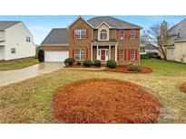 Charming two-story brick home with red shutters, well-manicured landscaping, and a two-car garage at 4828 Covington Nw Dr, Concord, NC 28027