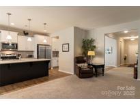 Open living space connecting to the kitchen with a comfortable recliner and view of hallway at 3156 Pinehills Way, Mount Holly, NC 28120