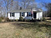 Charming one-story home with white siding, black shutters, and an American flag in a partially wooded area at 426 Holland Memorial Church Rd, Bessemer City, NC 28016