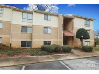 Tan brick and vinyl two-story condo with a covered entrance and front yard landscaping at 4822 Spring Lake Dr # A, Charlotte, NC 28212