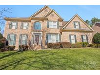 Beautiful brick two-story home with manicured lawn, arched window, and tasteful landscaping at 10101 Bayart Way, Huntersville, NC 28078