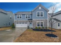 Charming two-story home featuring a stone facade, blue siding, attached garage, and well-manicured landscaping at 133 Batten Ridge Dr, Statesville, NC 28677