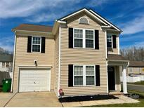 Charming two-story home with tan siding, black shutters, and a one-car garage under a bright blue sky at 13415 Tartarian Ct, Charlotte, NC 28215