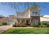 Charming two-story home with stone accents, covered porch, manicured lawn, and attached two car garage at 3216 Bridgewick Rd, Waxhaw, NC 28173
