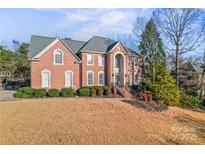 Beautiful two-story brick home with mature trees, manicured lawn, and a welcoming entrance at 4608 Snow Dr, Harrisburg, NC 28075