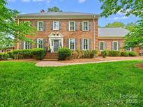 Charming brick home features lush landscaping, a well-manicured lawn, gray shutters, and an elegant entrance at 7329 Kennington Ct, Charlotte, NC 28270