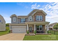 Charming two-story home with stone accents, gray siding, manicured lawn, and inviting front porch at 3008 Dundee Ln, Fort Mill, SC 29707