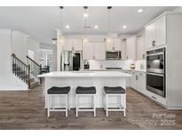 Modern kitchen with a central island, sleek white cabinetry, stainless steel appliances and stylish pendant lights at 3038 Lydney Cir, Waxhaw, NC 28173