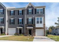 A gray townhome exterior features a brick facade, attached garage, and well-maintained front yard at 3104 Beeler Ln, Charlotte, NC 28208